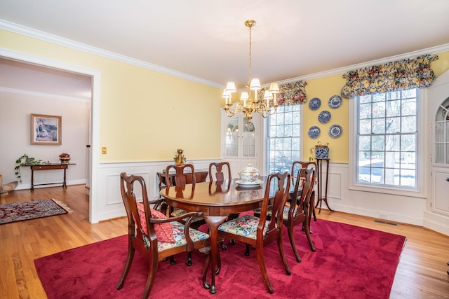 dining area with hardwood / wood-style flooring, ornamental molding, and a notable chandelier