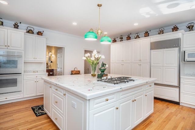 kitchen featuring white cabinetry, hanging light fixtures, paneled built in refrigerator, double wall oven, and a center island