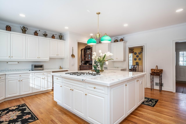 kitchen with white gas cooktop, decorative light fixtures, a kitchen island, and white cabinets