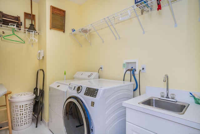 clothes washing area featuring cabinets, washing machine and clothes dryer, and sink