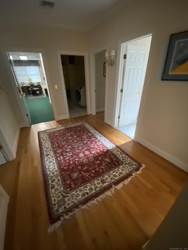 corridor with washer / clothes dryer and light hardwood / wood-style flooring