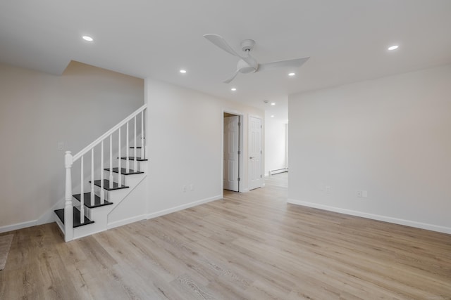 unfurnished room with ceiling fan, a baseboard radiator, and light wood-type flooring