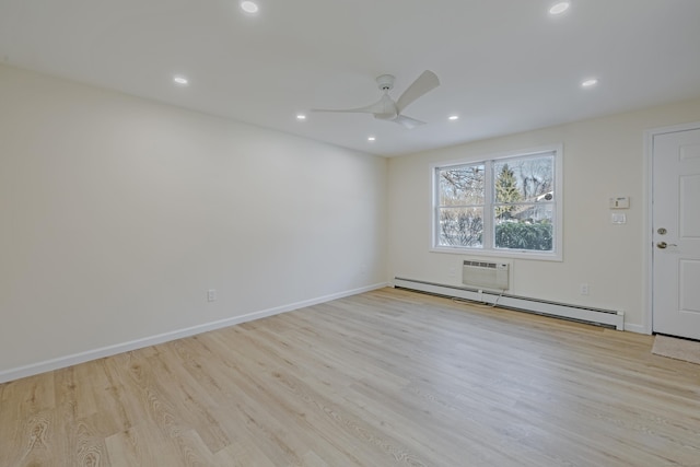 unfurnished room with ceiling fan, a baseboard heating unit, a wall unit AC, and light hardwood / wood-style floors