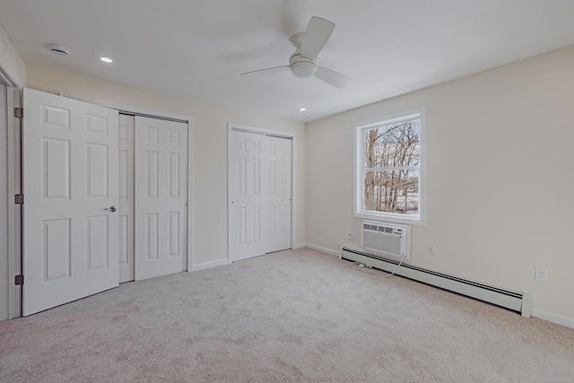 unfurnished bedroom featuring a wall mounted AC, light carpet, baseboard heating, two closets, and ceiling fan