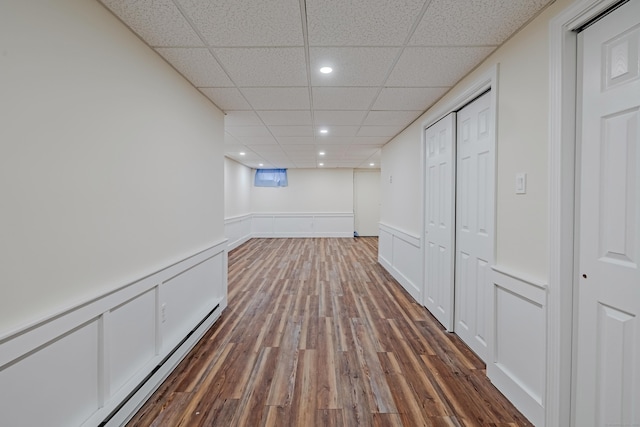 interior space with dark hardwood / wood-style floors, a paneled ceiling, and baseboard heating