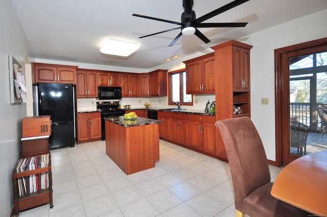 kitchen featuring sink, ceiling fan, a center island, black appliances, and dark stone counters