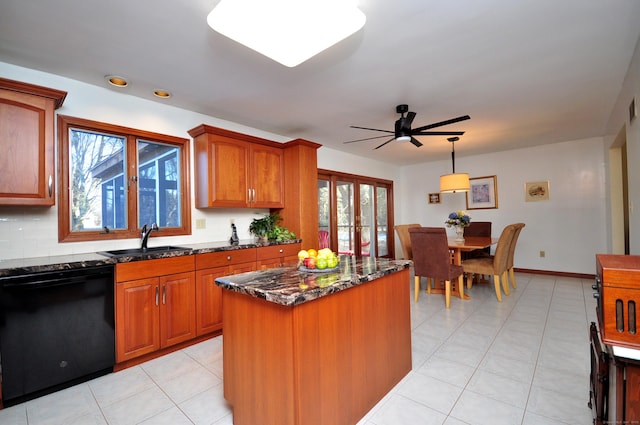 kitchen with dishwashing machine, sink, dark stone countertops, a center island, and decorative light fixtures