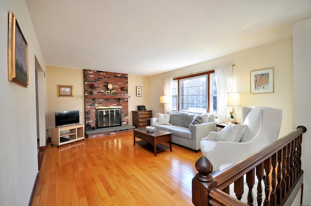 living room with wood-type flooring and a brick fireplace