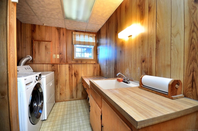 laundry room with cabinets, sink, washer and dryer, and wood walls