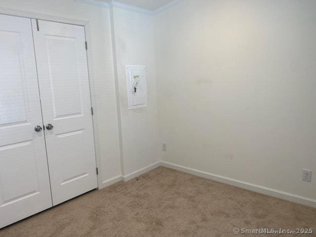 unfurnished bedroom with a closet, ornamental molding, and light carpet