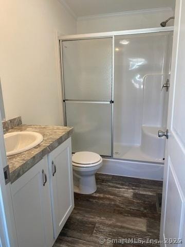 bathroom featuring toilet, an enclosed shower, ornamental molding, vanity, and hardwood / wood-style floors