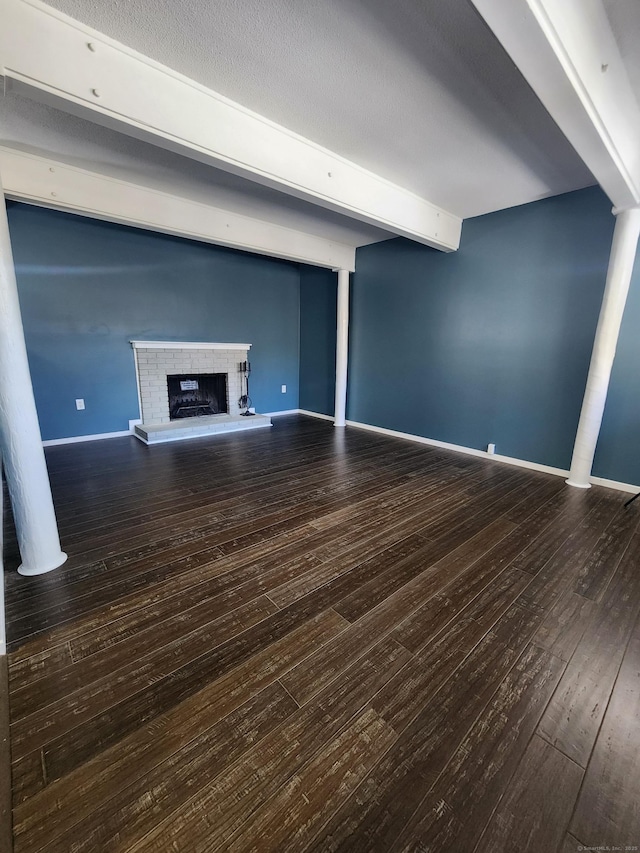 unfurnished living room featuring a brick fireplace, beam ceiling, and wood-type flooring