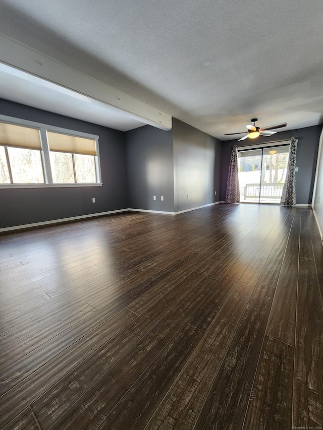 spare room with dark wood-type flooring, a textured ceiling, and a wealth of natural light