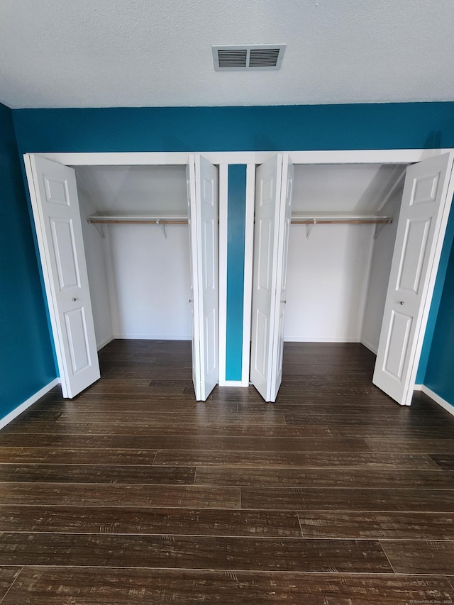 unfurnished bedroom featuring multiple closets and dark hardwood / wood-style flooring