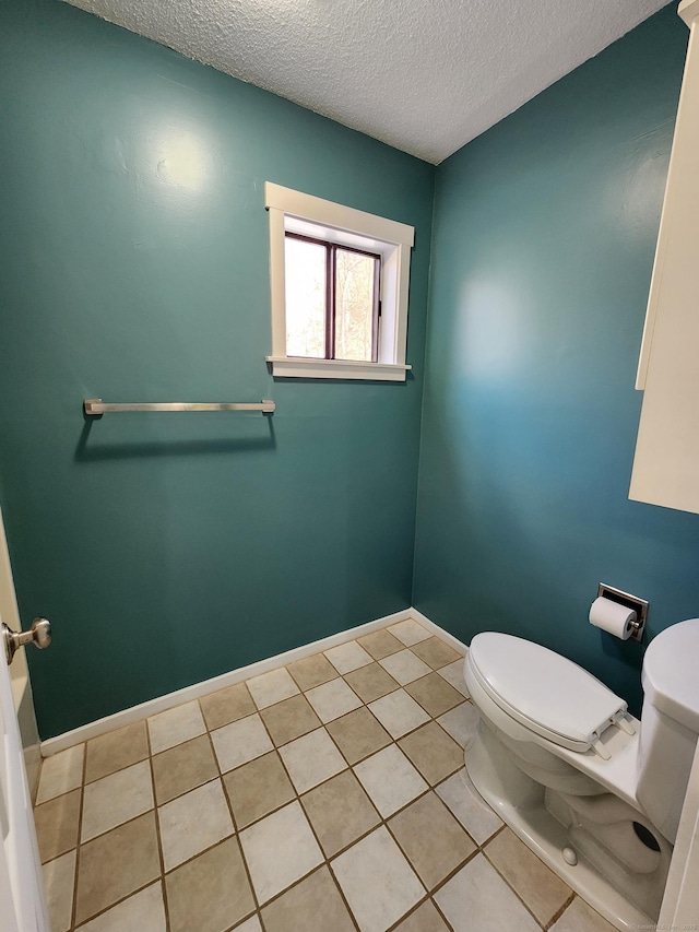 bathroom with tile patterned flooring, a textured ceiling, and toilet