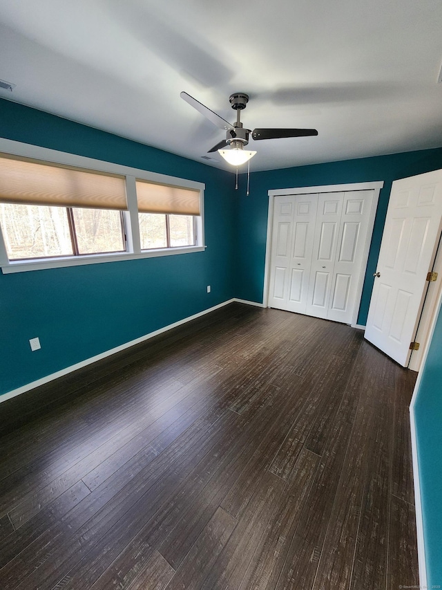 unfurnished bedroom featuring dark hardwood / wood-style floors, ceiling fan, and a closet