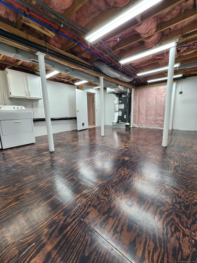 basement featuring washer / dryer, dark hardwood / wood-style floors, and heating unit