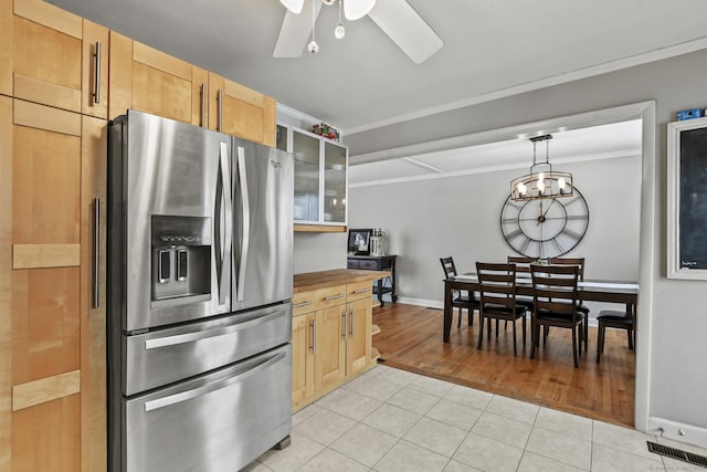 kitchen featuring pendant lighting, light tile patterned floors, crown molding, stainless steel fridge, and light brown cabinetry