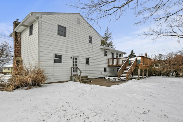 snow covered rear of property featuring a deck