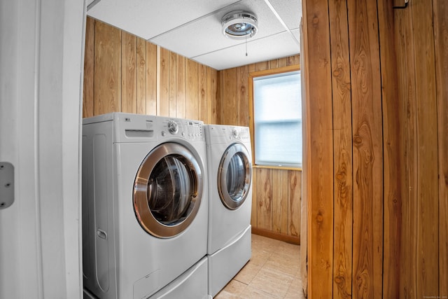 clothes washing area featuring wooden walls and independent washer and dryer