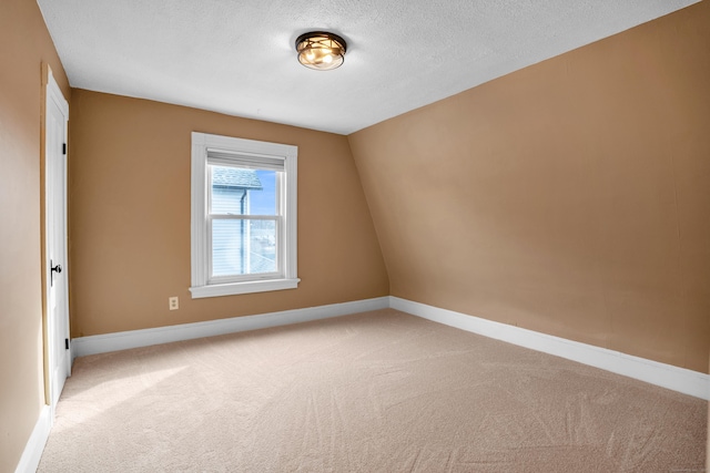 carpeted spare room featuring lofted ceiling and a textured ceiling