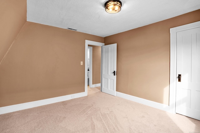 unfurnished bedroom featuring light colored carpet and a textured ceiling