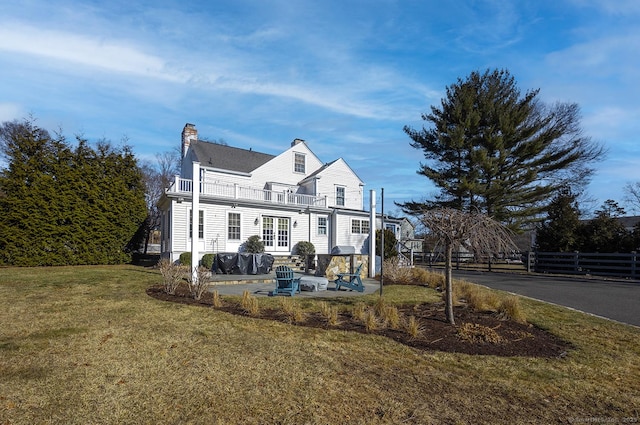 rear view of house featuring a balcony, a patio area, and a lawn