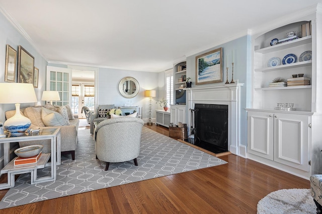 living room featuring built in features, dark wood-type flooring, and ornamental molding