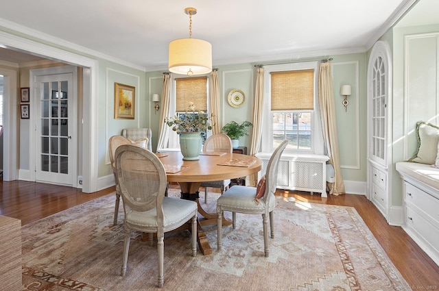 dining room with hardwood / wood-style flooring, ornamental molding, and radiator