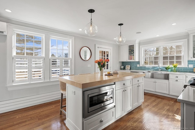 kitchen featuring a kitchen island, sink, stainless steel microwave, and white cabinets