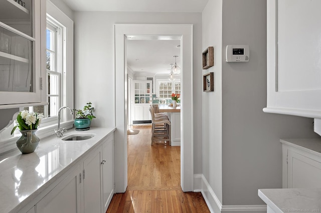 bar with sink, white cabinetry, light stone counters, light wood-type flooring, and a wealth of natural light