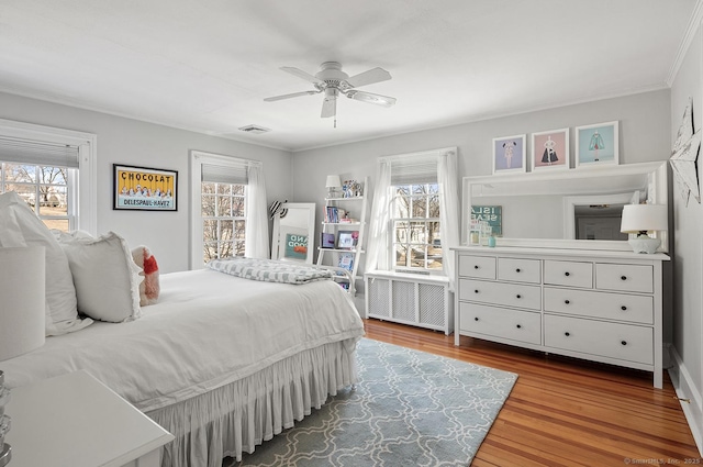 bedroom featuring crown molding, ceiling fan, radiator heating unit, and wood-type flooring