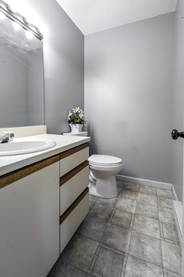 bathroom featuring vanity, a textured ceiling, and toilet