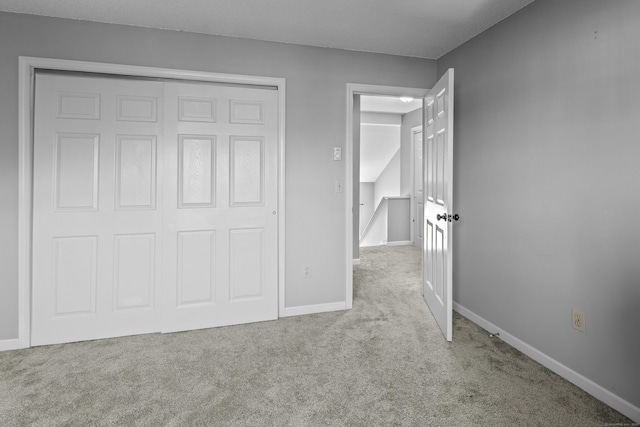 unfurnished bedroom featuring light colored carpet and a closet