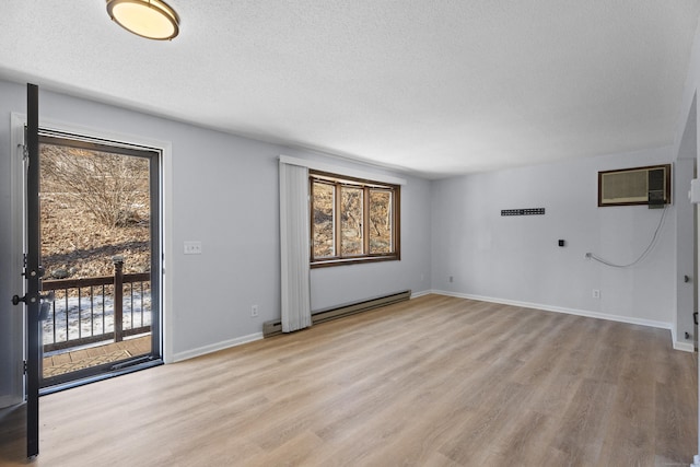 empty room with a wall mounted AC, light hardwood / wood-style flooring, and a wealth of natural light