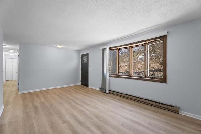 spare room featuring a baseboard radiator, a textured ceiling, and light wood-type flooring