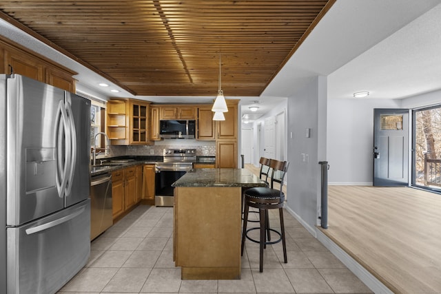 kitchen featuring appliances with stainless steel finishes, a breakfast bar, decorative light fixtures, sink, and a center island