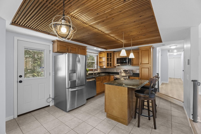 kitchen featuring light tile patterned flooring, sink, a center island, hanging light fixtures, and appliances with stainless steel finishes