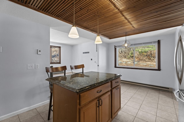 kitchen featuring a kitchen island, dark stone countertops, a kitchen breakfast bar, hanging light fixtures, and a baseboard heating unit