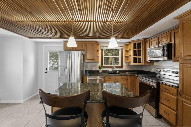 kitchen featuring light tile patterned floors, sink, hanging light fixtures, stainless steel appliances, and dark stone counters