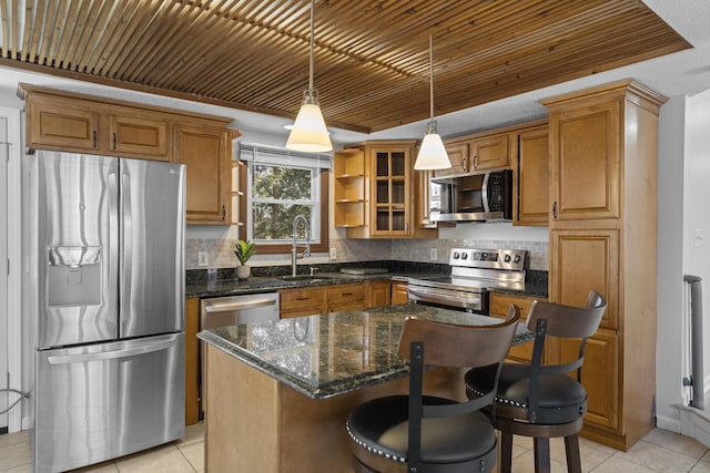 kitchen featuring hanging light fixtures, dark stone countertops, appliances with stainless steel finishes, a kitchen island, and backsplash