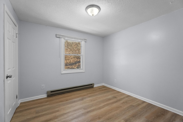 empty room featuring wood-type flooring, a textured ceiling, and baseboard heating