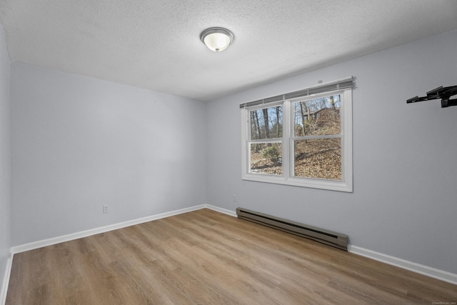 spare room featuring light hardwood / wood-style floors, a textured ceiling, and baseboard heating