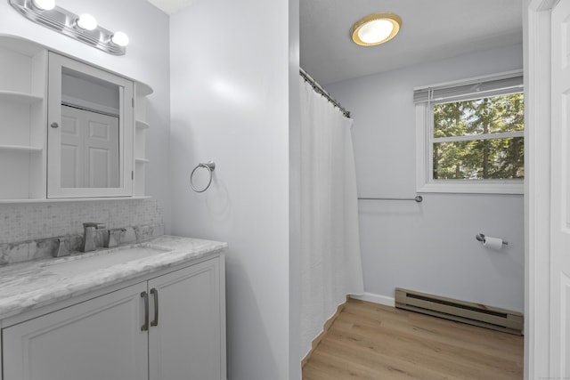 bathroom with hardwood / wood-style flooring, a baseboard radiator, vanity, and decorative backsplash