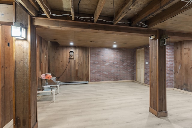 basement with brick wall, wooden walls, light hardwood / wood-style flooring, and a baseboard heating unit