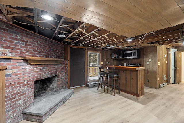 bar featuring a baseboard radiator, wooden walls, a fireplace, and light hardwood / wood-style floors