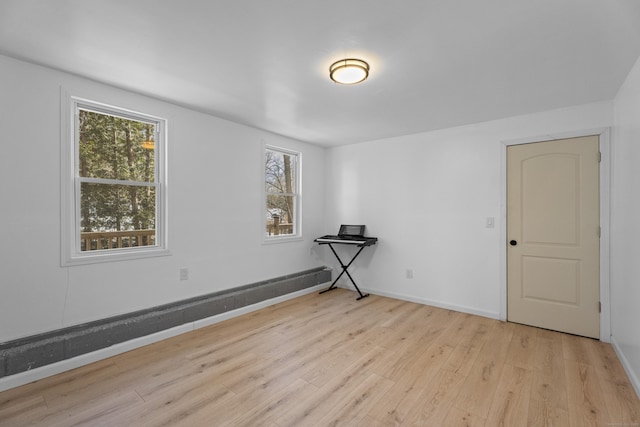 spare room with a baseboard radiator and light hardwood / wood-style floors