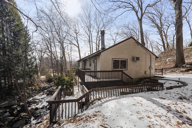 snow covered property with a wooden deck and an AC wall unit