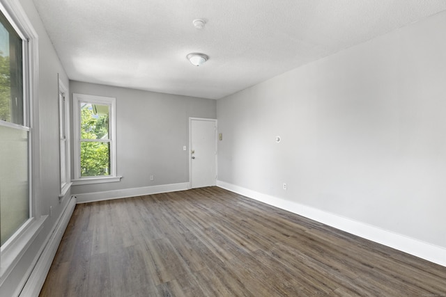 spare room featuring dark wood-type flooring, a textured ceiling, and baseboard heating