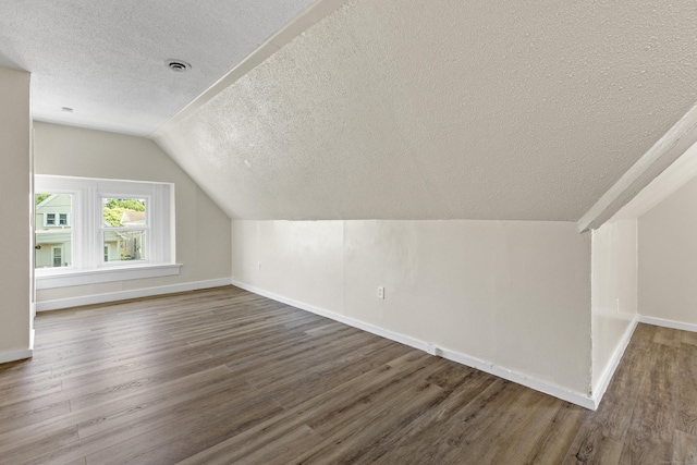 bonus room featuring vaulted ceiling, dark wood-type flooring, and a textured ceiling